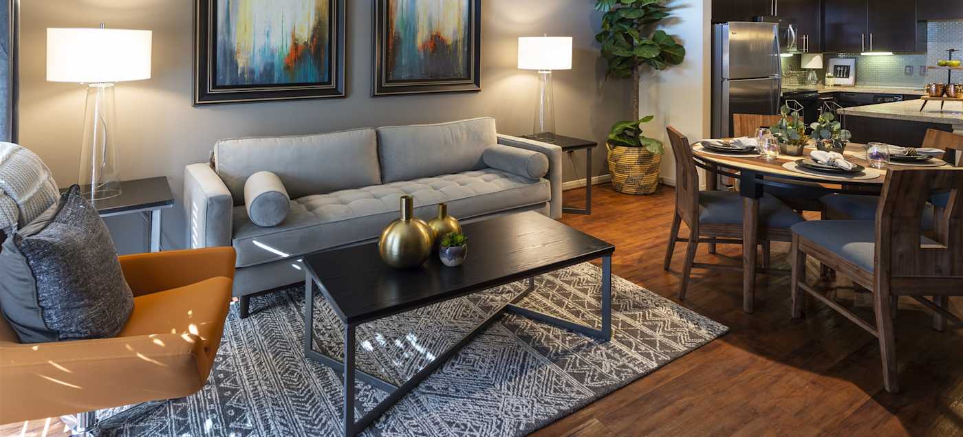 A furnished living room with a sofa and the dining area behind it