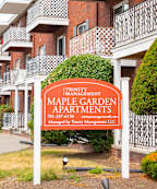 A red brick apartment building with a sign that says Maple Garden Apartments.