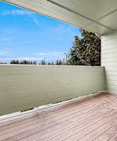 A wooden deck with a white wall and a window.