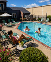 A woman in a pink bikini relaxes by a pool with two children.