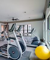 A gym with a variety of exercise equipment including treadmills, stationary bikes, and weight machines.
