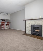 an empty living room with a fireplace and a kitchen at Lincoln Village Apartments, Spokane