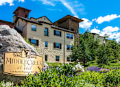 Thumbnail 1 of 19 - A large rock with a sign that says Middle Creek at Vail in front of a building.