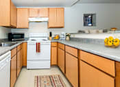 Thumbnail 6 of 19 - A kitchen with a white stove and wooden cabinets.