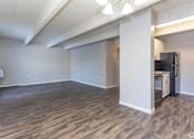Thumbnail 25 of 27 - A room with a black fridge and wooden flooring.