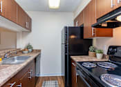 Thumbnail 23 of 24 - A kitchen with a black refrigerator and a black stove top oven. at Monaco Lakes, Denver, CO, 80222