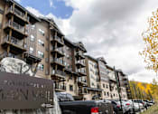 Thumbnail 1 of 10 - A large apartment complex named "Main Vail" is shown with cars parked in front.