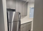 Thumbnail 42 of 82 - A stainless steel refrigerator in a kitchen with wooden flooring and white walls.