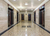 Thumbnail 20 of 74 - A long hallway with marble floors and doors on both sides.