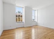Thumbnail 68 of 74 - A large empty room with wooden floors and two windows.