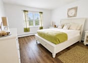 Thumbnail 4 of 9 - A bedroom with a white bed and a green blanket.