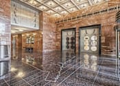 Thumbnail 7 of 74 - A hallway with a marble floor and a brown wall.