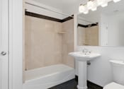 Thumbnail 61 of 74 - A white bathroom with a tub, sink, and mirror.
