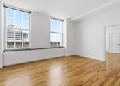 Thumbnail 62 of 74 - A room with wooden floors and a large window overlooking a cityscape.