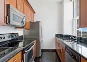 Thumbnail 59 of 74 - A kitchen with a black counter top and stainless steel appliances.