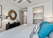 Thumbnail 25 of 39 - a bedroom with a large bed and a mirror on the wall with ceiling fan at LynnCora, Grand Prairie, TX