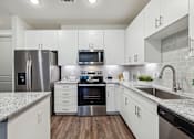 Thumbnail 30 of 39 - an empty kitchen with white cabinets and stainless steel appliances at LynnCora, Texas