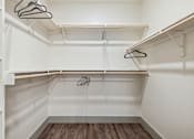 Thumbnail 36 of 39 - a spacious walk in closet with white walls and wood flooring at LynnCora, Grand Prairie, TX, 75052