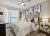 Thumbnail 37 of 39 - Model apartment bedroom with large window and ceiling fan at LynnCora, Grand Prairie, Texas