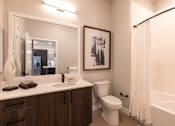 Thumbnail 5 of 18 - A bathroom with a vanity, sink, toilet and showernd a white bathtub.