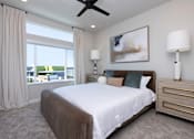 Thumbnail 4 of 18 - A bedroom with a large bed, large windows and a ceiling fan