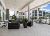 Thumbnail 8 of 79 - a large patio with furniture and a pool in front of an apartment building at Mira at Palmer Ranch in Sarasota, FL
