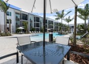 Thumbnail 5 of 79 - a patio with a table and chairs in front of an apartment building at Mira at Palmer Ranch in Sarasota, FL