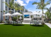 Thumbnail 14 of 79 - a patio with tables and umbrellas in front of a building at Mira at Palmer Ranch in Sarasota, FL