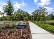 Thumbnail 15 of 79 - a sign for the butterfly garden next to a sidewalk at Mira at Palmer Ranch in Sarasota, FL