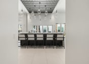 Thumbnail 30 of 79 - the kitchen has a large island with chairs and a row of hanging lights at Mira at Palmer Ranch in Sarasota, FL