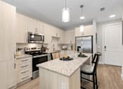 Thumbnail 67 of 79 - a kitchen with a large island with a granite counter top and stainless steel appliances at Mira at Palmer Ranch, Sarasota, FL