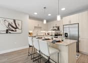 Thumbnail 48 of 79 - a kitchen with a island with white chairs and a stainless steel refrigerator at Mira at Palmer Ranch, Florida