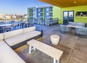 Thumbnail 8 of 23 - Outdoor balcony resident lounge with  large screen tv , seating and table and chairs at Zeta Luxury Apartments in Sacramento, CA