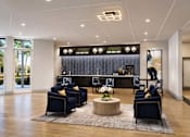 Thumbnail 8 of 15 - A modern living room with a dark blue sofa set and a wooden coffee table.