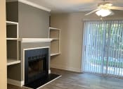 Thumbnail 6 of 10 - An unfurnished living room with a fireplace and a sliding glass door.