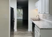 Thumbnail 9 of 10 - A kitchen with white cabinets and a black refrigerator.