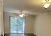 Thumbnail 7 of 10 - An unfurnished living room with a sliding glass door.