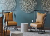 Thumbnail 16 of 29 - a living room with two orange chairs and two round stools in front of a green wall