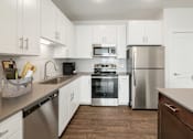 Thumbnail 7 of 30 - A kitchen with white cabinets and stainless steel appliances.