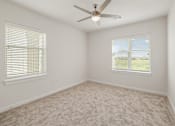 Thumbnail 6 of 30 - A room with a ceiling fan and two windows.