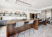 Thumbnail 4 of 35 - A modern kitchen with a long wooden island and four chairs.