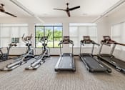 Thumbnail 21 of 35 - A room with a row of treadmills and elliptical machines.