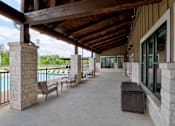 Thumbnail 6 of 35 - A covered patio area with a pool in the background.