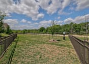 Thumbnail 16 of 35 - A dog park with a fence and a few trees.