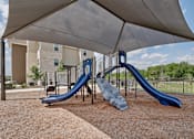 Thumbnail 12 of 35 - A playground with a blue slide and a grey canopy.