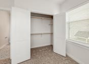 Thumbnail 7 of 35 - A white closet with a carpeted floor and a window with blinds.