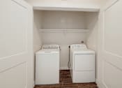 Thumbnail 33 of 35 - Two white front loading washing machines in a small laundry room.