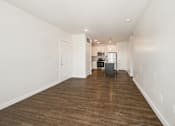 Thumbnail 9 of 35 - A long, empty hallway with wooden floors and white walls.