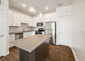 Thumbnail 30 of 35 - A kitchen with a stainless steel refrigerator and a wooden island.