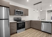 Thumbnail 16 of 28 - A modern kitchen with stainless steel appliances and wooden flooring.